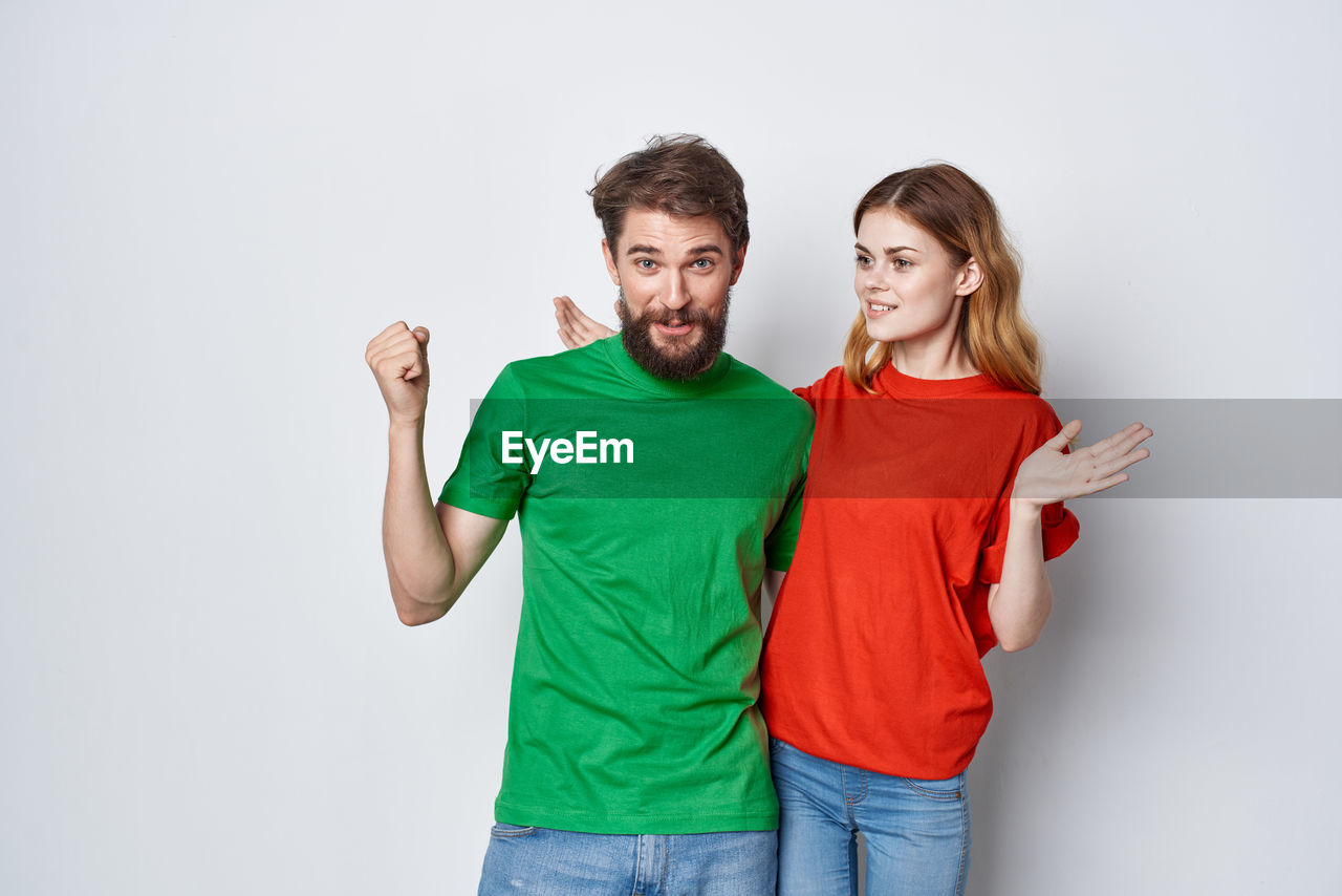 FULL LENGTH PORTRAIT OF YOUNG COUPLE STANDING AGAINST WHITE BACKGROUND