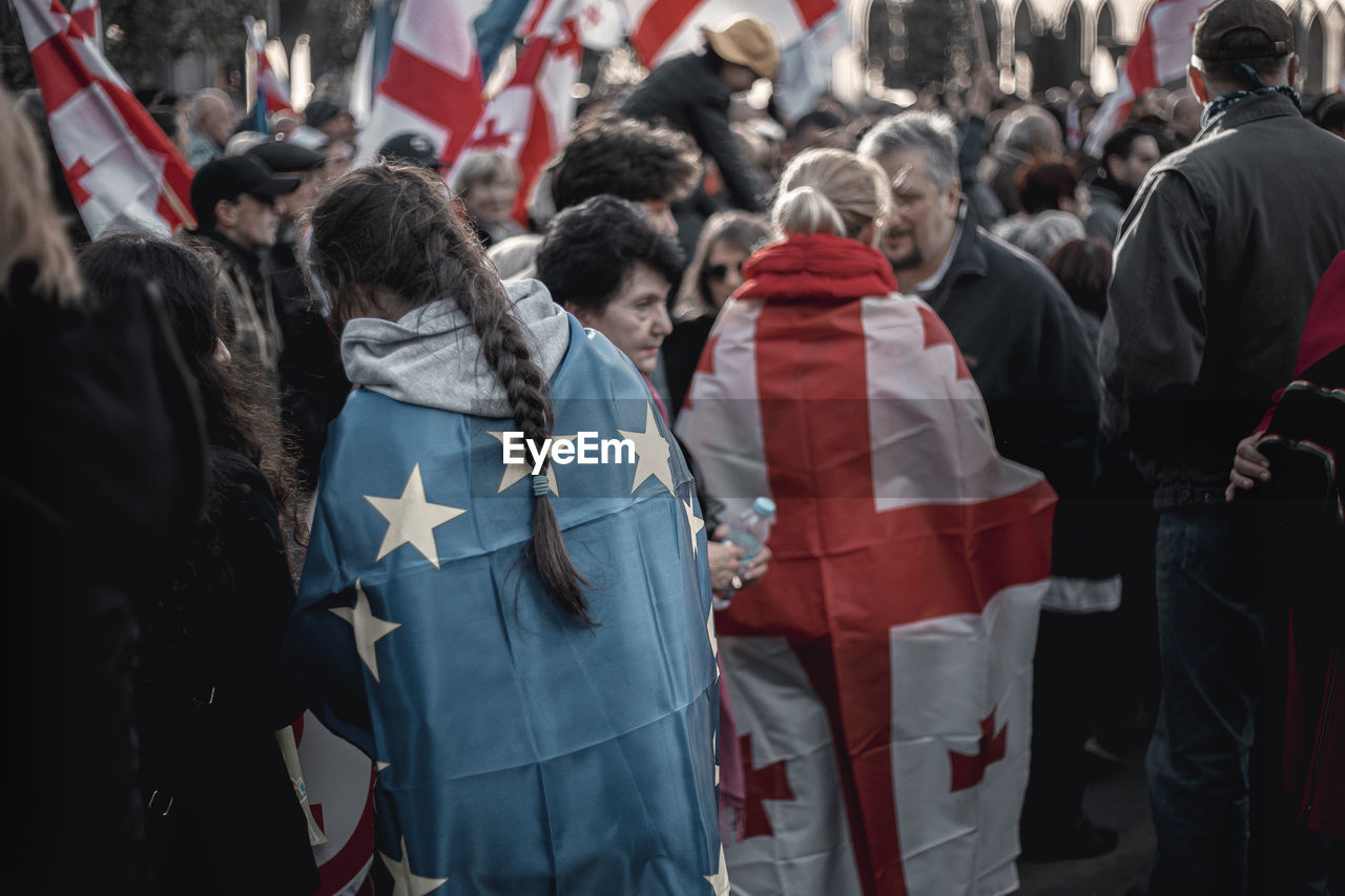 Crowd with flags protesting on street in city