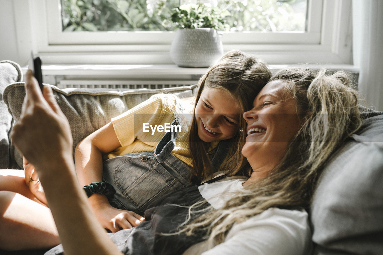 Smiling mother and daughter using digital tablet in living room