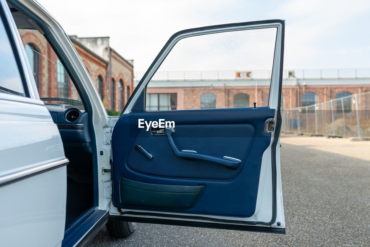 Open car front door with a brick building in the background