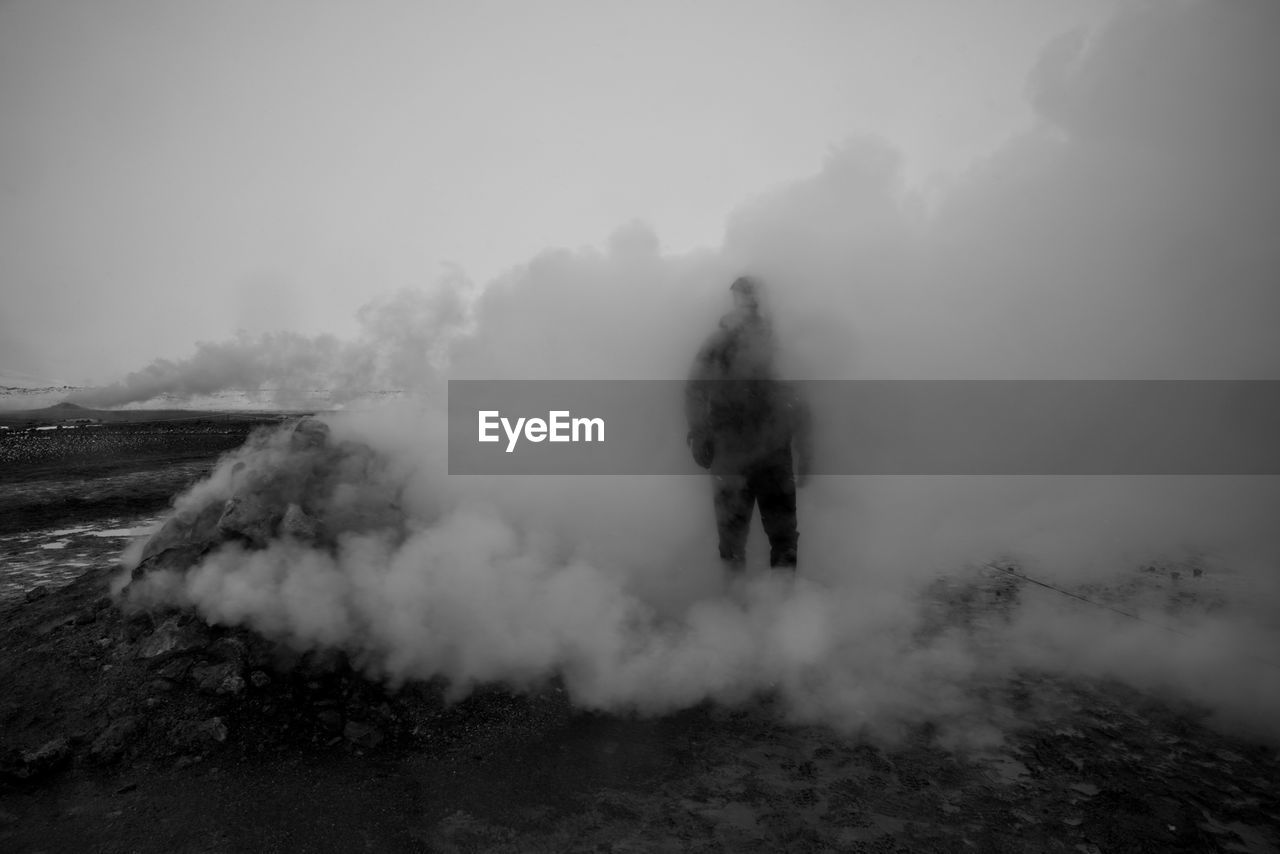 Person standing amidst smoke at volcanic landscape