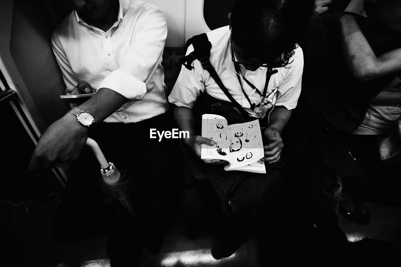 High angle view of man reading comic book while traveling in train