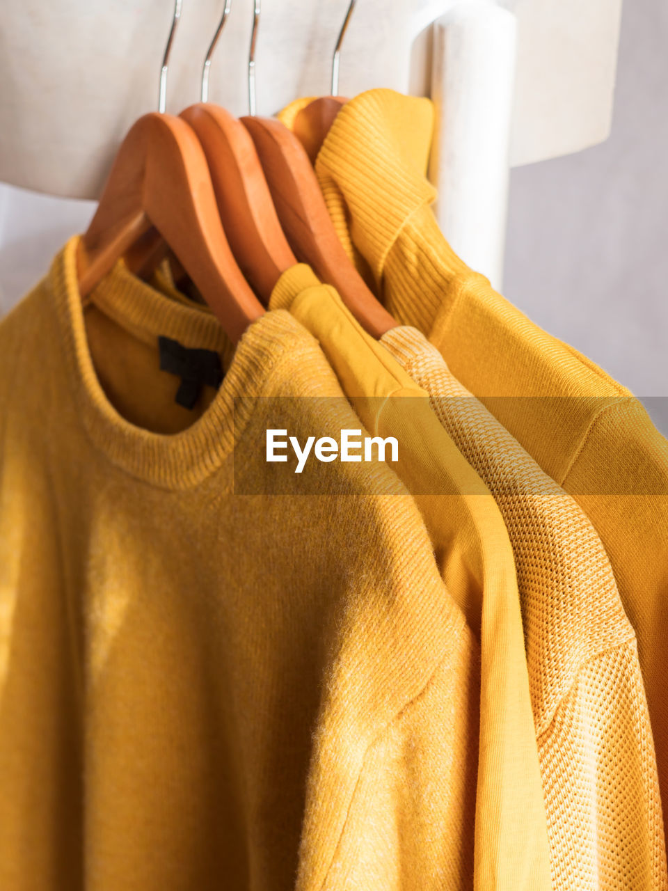 Yellow illuminated color winter sweaters on wooden hangers. trendy fashion autumn warm  clothes.