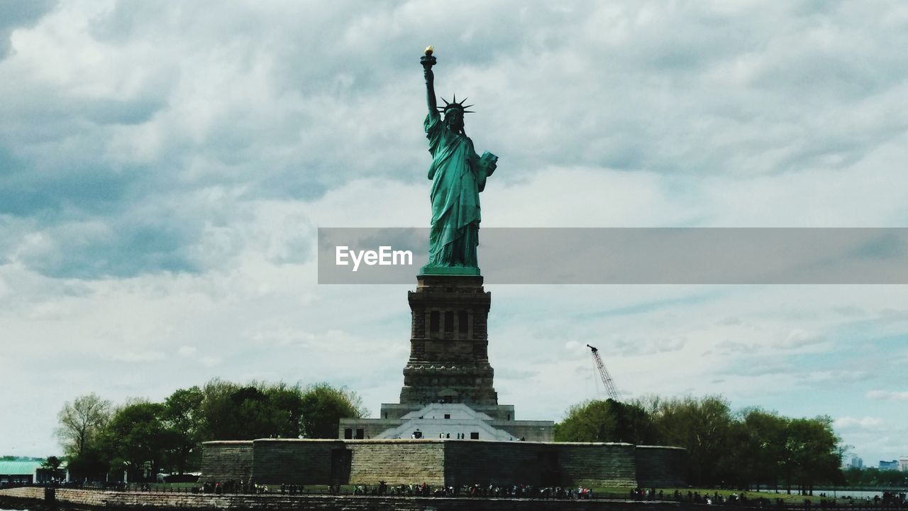 LOW ANGLE VIEW OF STATUE OF LIBERTY AGAINST CLOUDY SKY