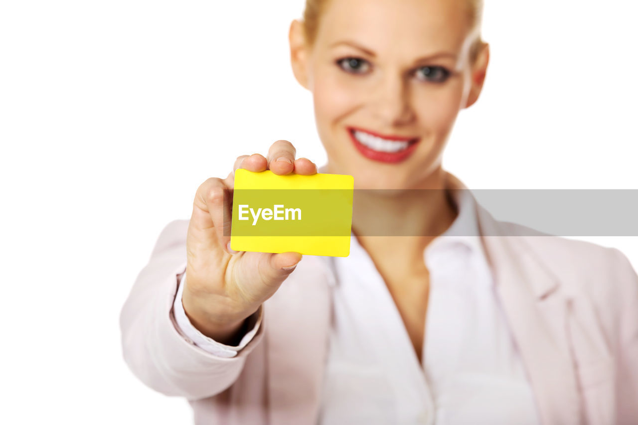 Portrait of smiling businesswoman holding yellow card against white background