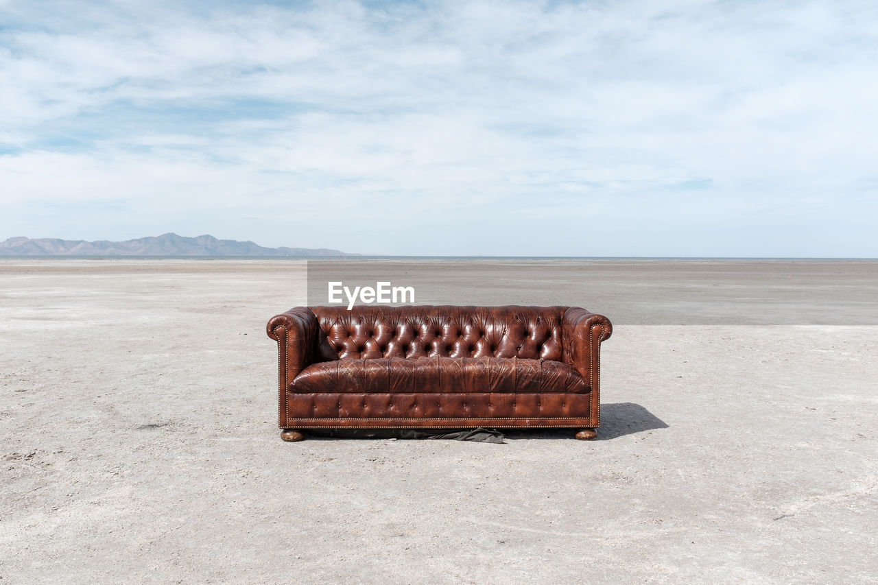 Sofa at salt flat against sky