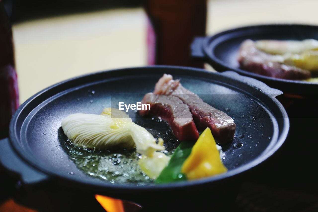 Food cooking in pans on gas stove burner at kitchen