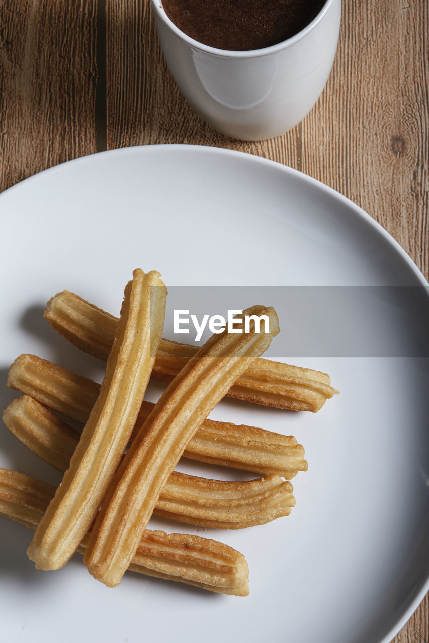 Churros with chocolate on wooden background. isolated and vertical image
