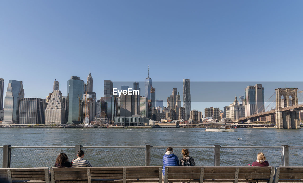 People sitting on bench while looking at city