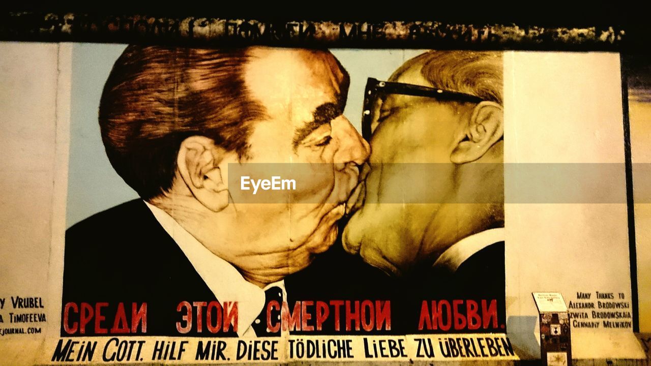 CLOSE-UP OF COUPLE KISSING WITH TEXT ON WALL