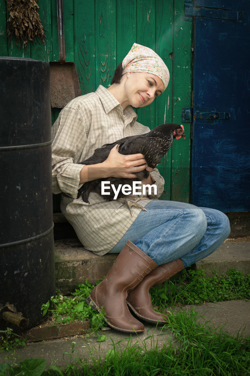 Woman sitting with chicken by door