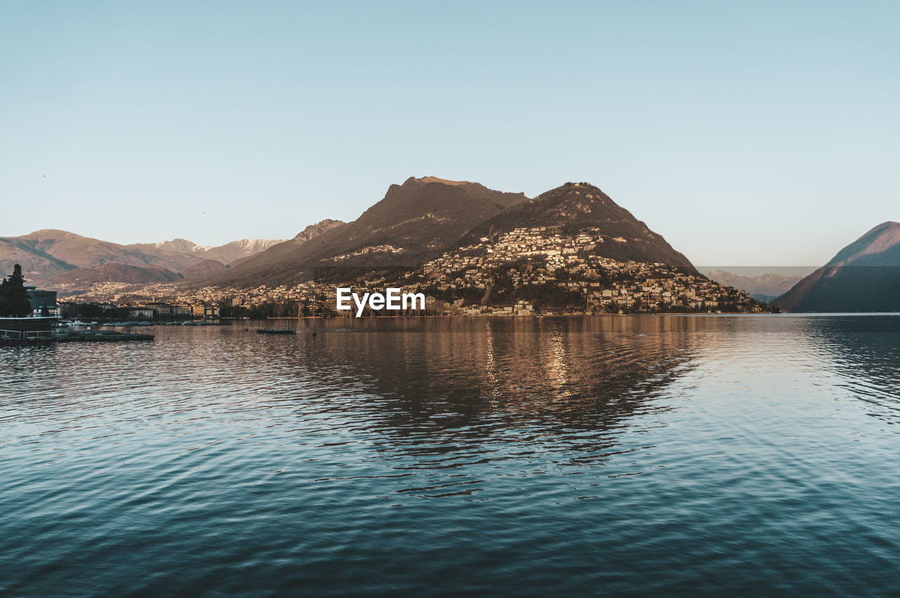 LAKE BY MOUNTAINS AGAINST CLEAR SKY