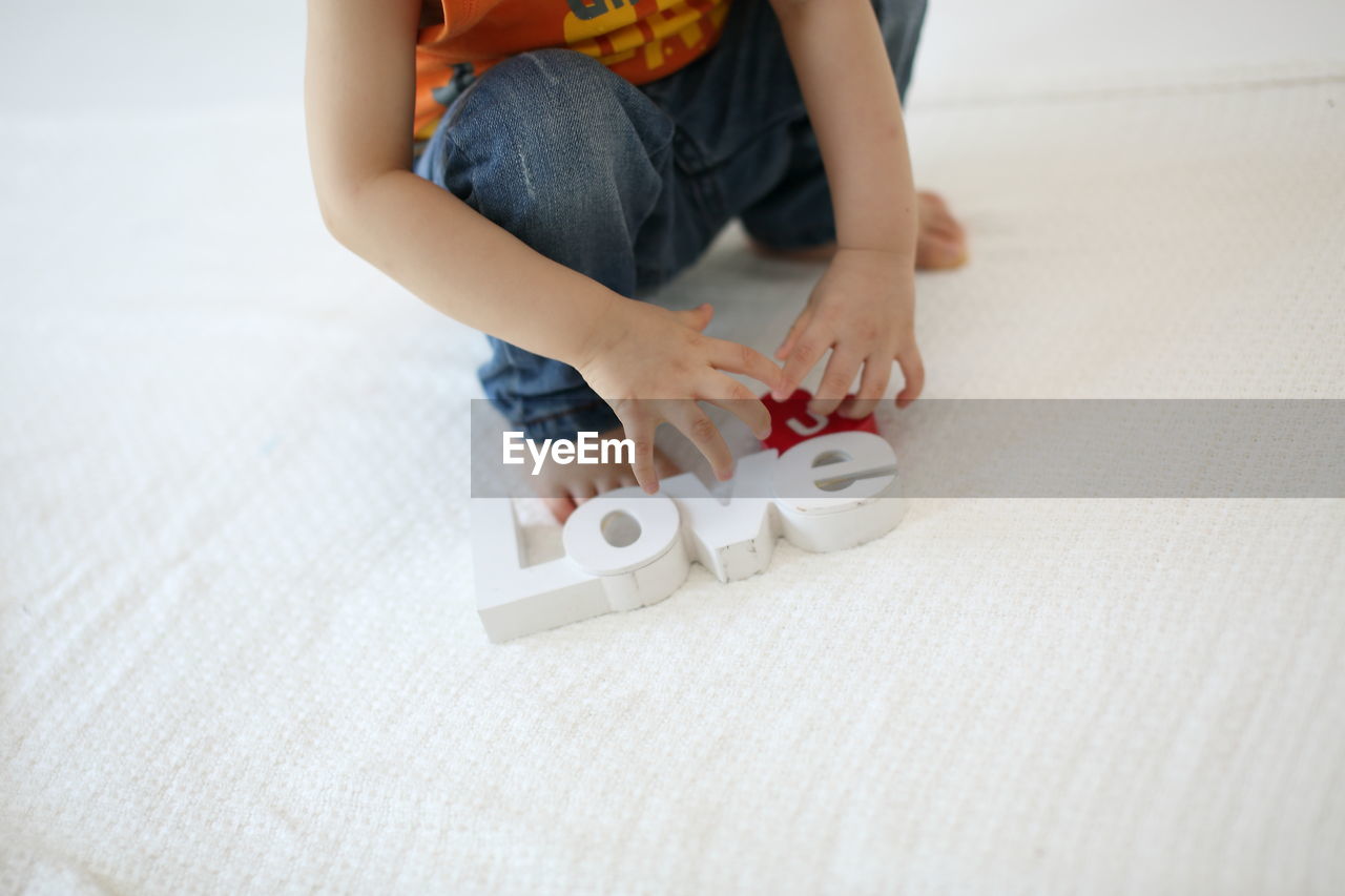 Low section of baby boy playing with toy at home