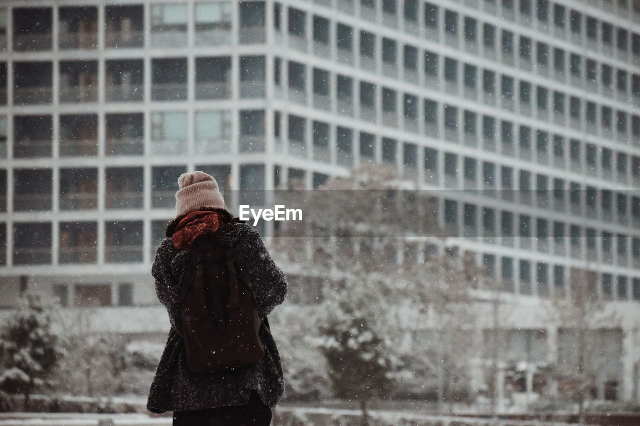 Rear view of woman standing in city during winter