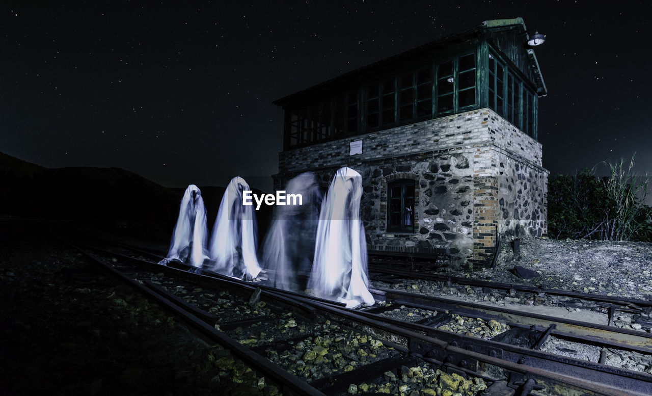 Group of ghosts walking on railroad track at night