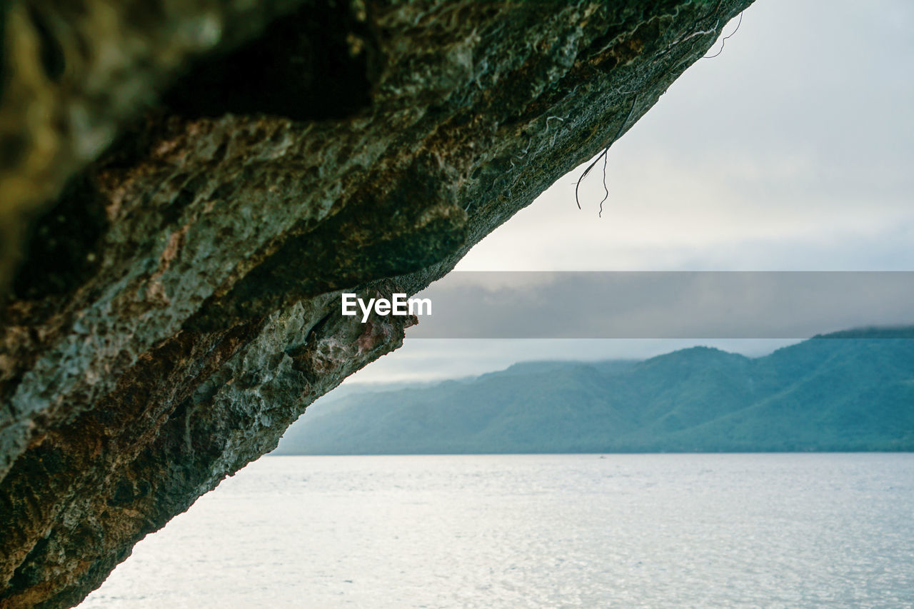 Scenic view of sea by mountains against sky