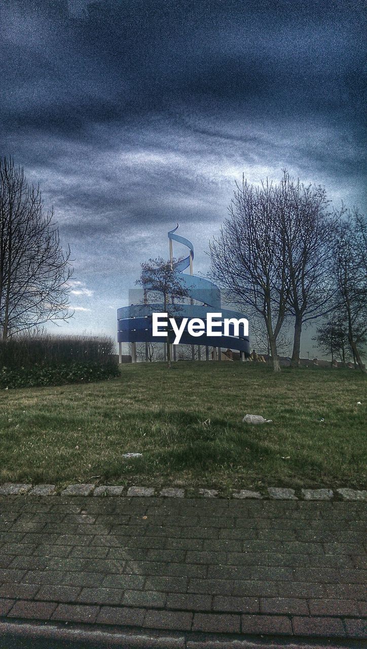 TREES ON FIELD AGAINST CLOUDY SKY