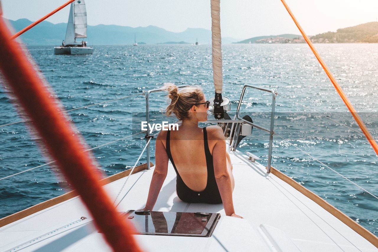 Rear view of woman traveling in yacht sailing on sea