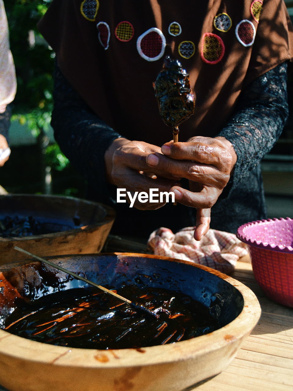 Midsection of man holding food on table while standing outdoors