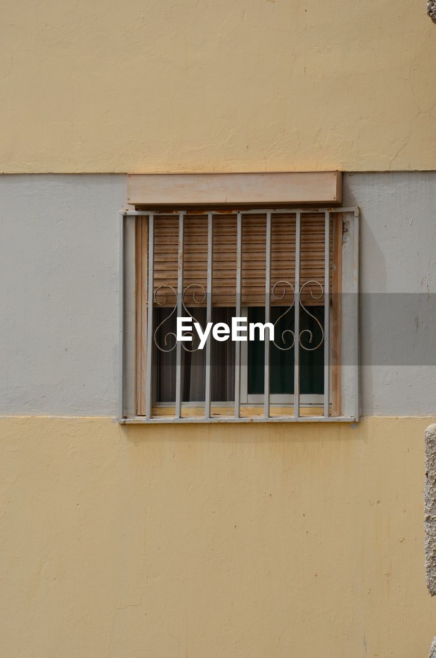 Barred window on yellow building wall