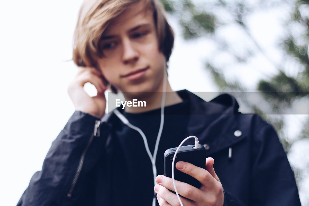 Teenage boy listening music while standing outdoors
