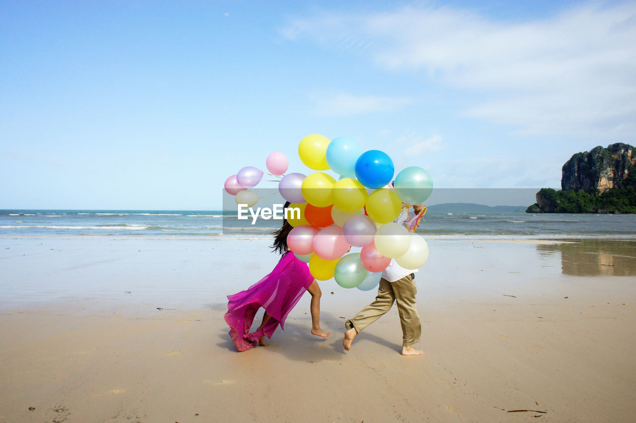 Couple walking on beach with balloons