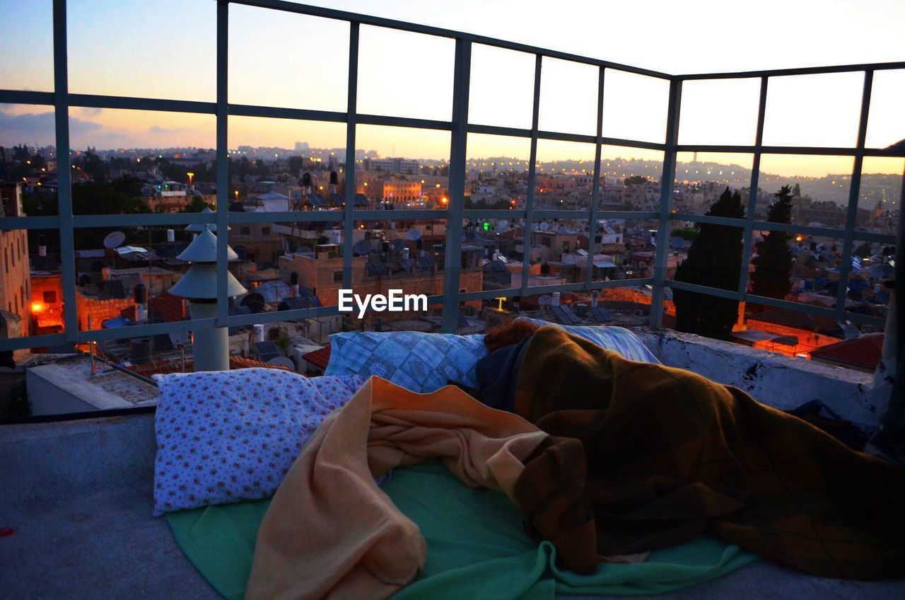 High angle view of woman sleeping on building terrace during sunrise