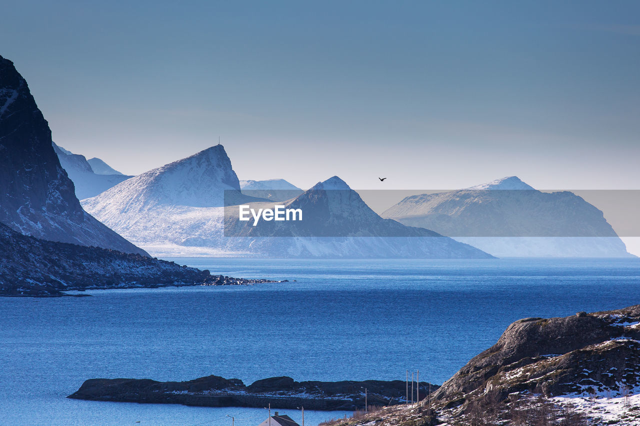 Scenic view of sea and snowcapped mountains against sky