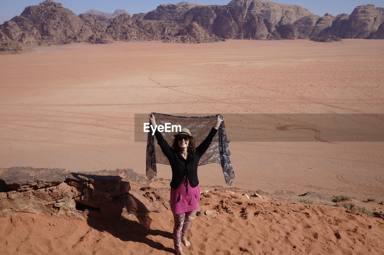 Woman with umbrella on sand dune in desert