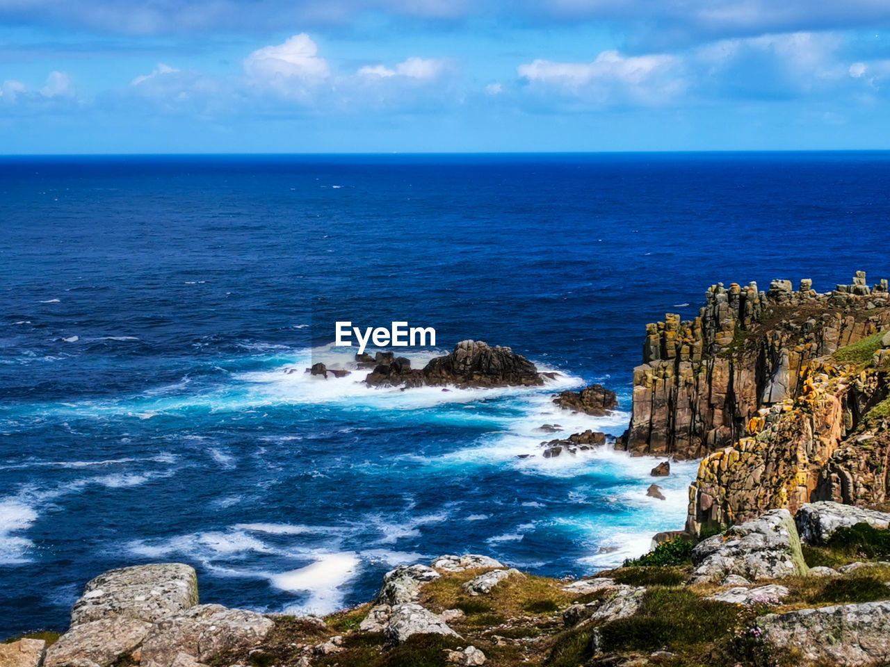 ROCKS BY SEA AGAINST SKY