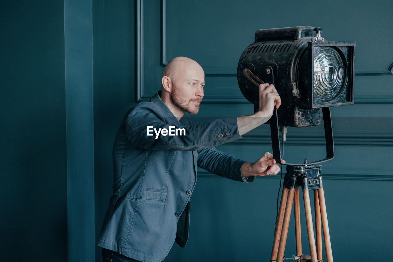  male photographer adjusting lighting equipment while standing by wall