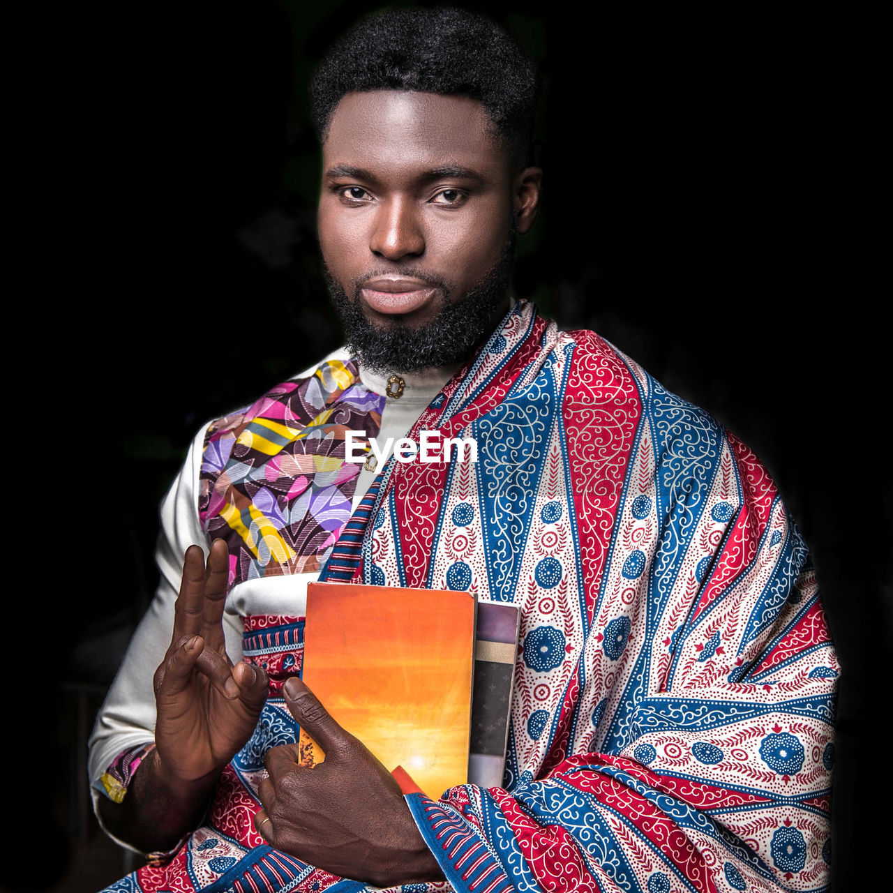 Portrait of man in traditional clothing gesturing against black background