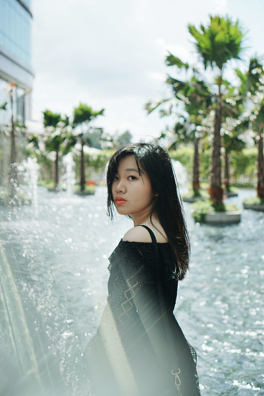 Portrait of beautiful woman standing by fountain