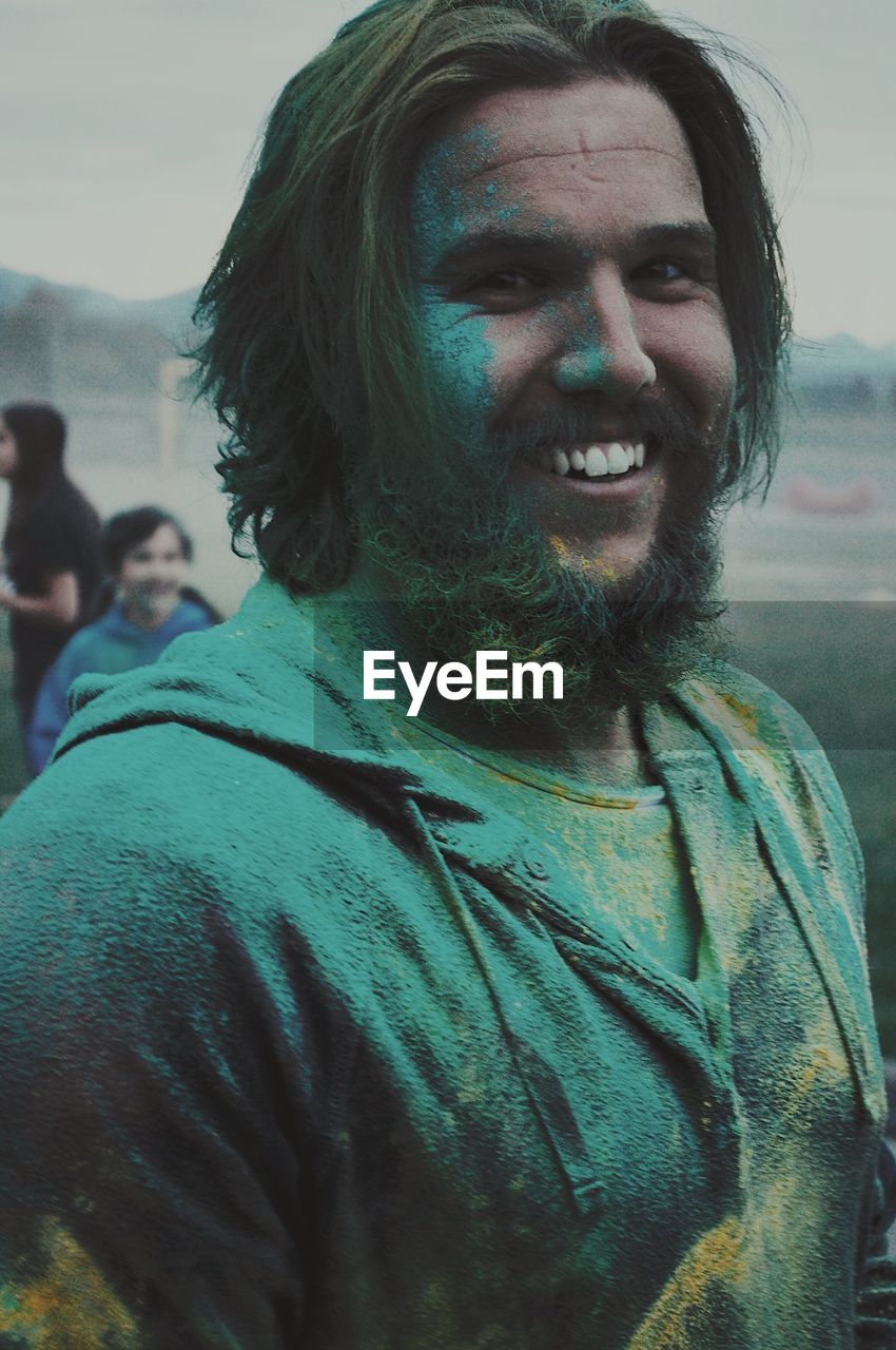 Portrait of smiling man covered with green powder paint