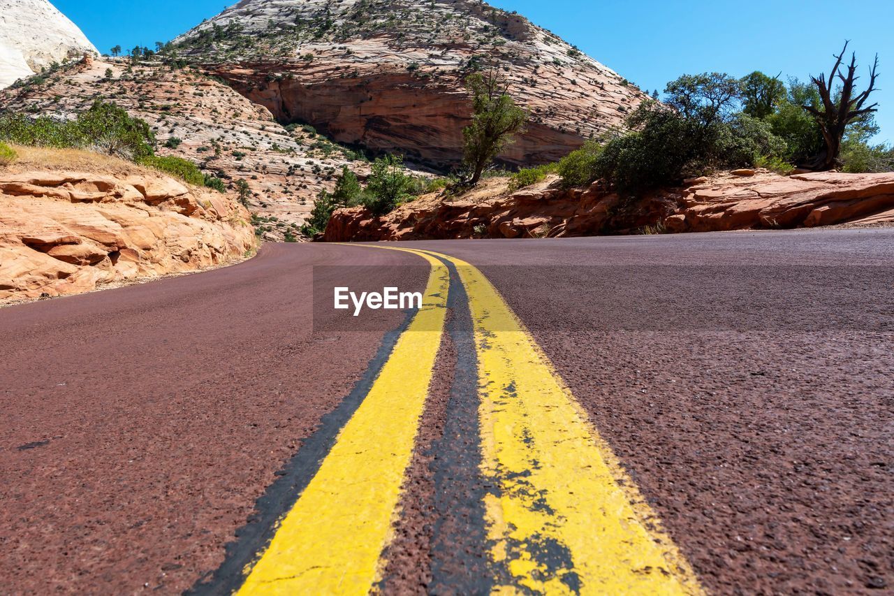 Surface level of road amidst rocks against sky with leading lines