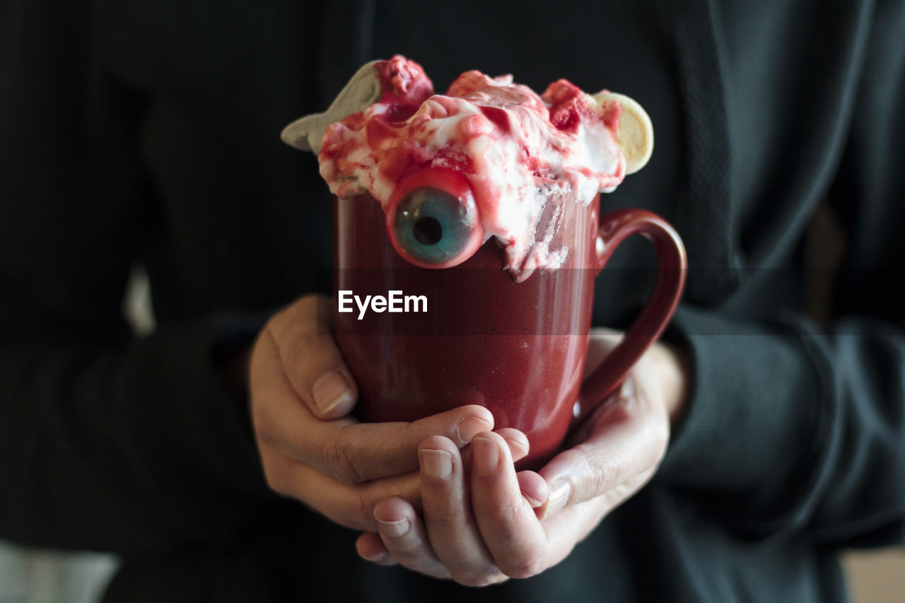 Woman holding mug with halloween drink