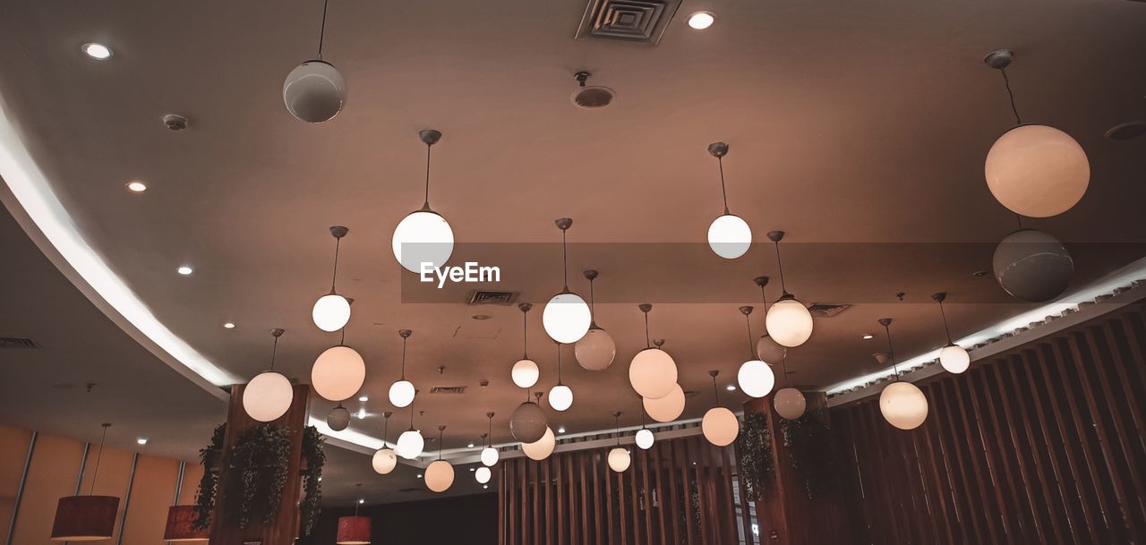 LOW ANGLE VIEW OF ILLUMINATED LIGHTS HANGING ON CEILING