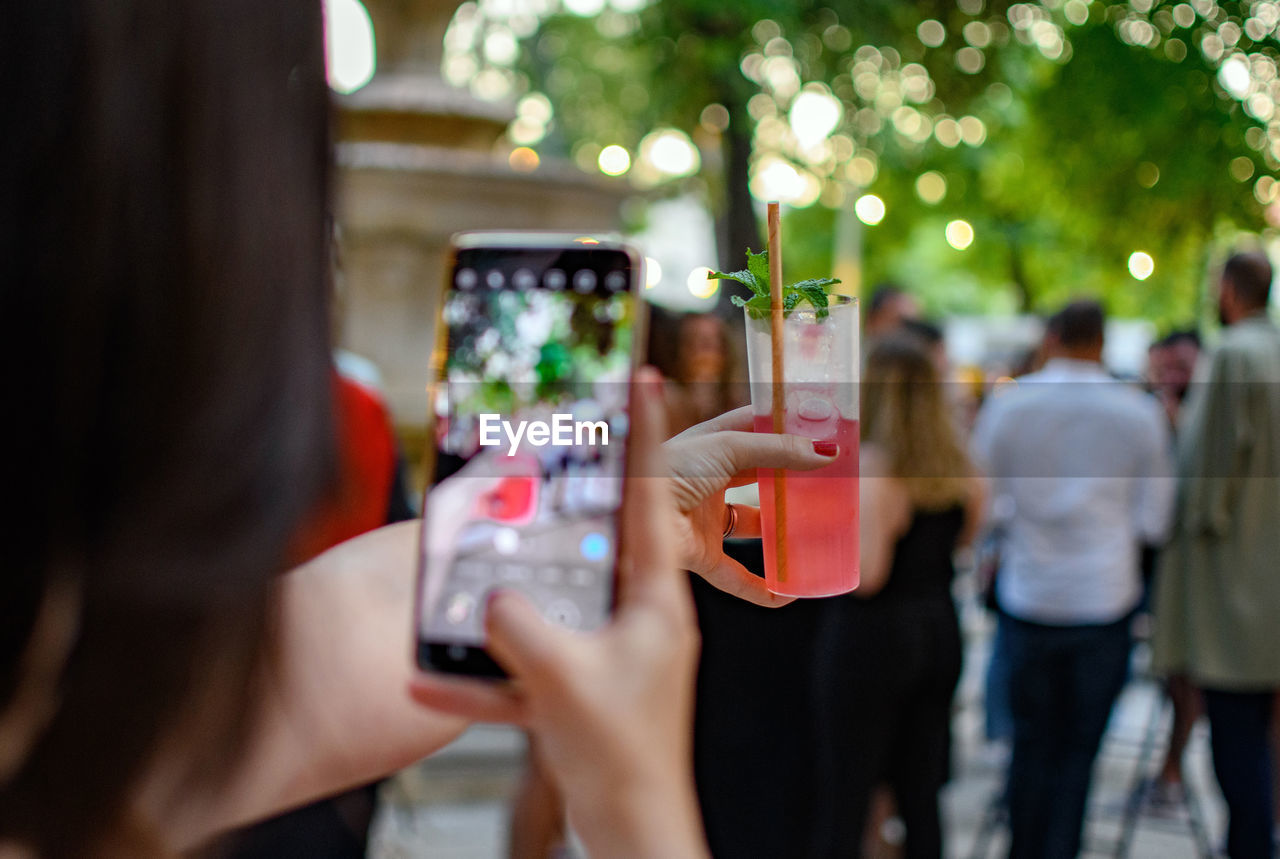 Selective focus image of woman taking photo of her cocktail.