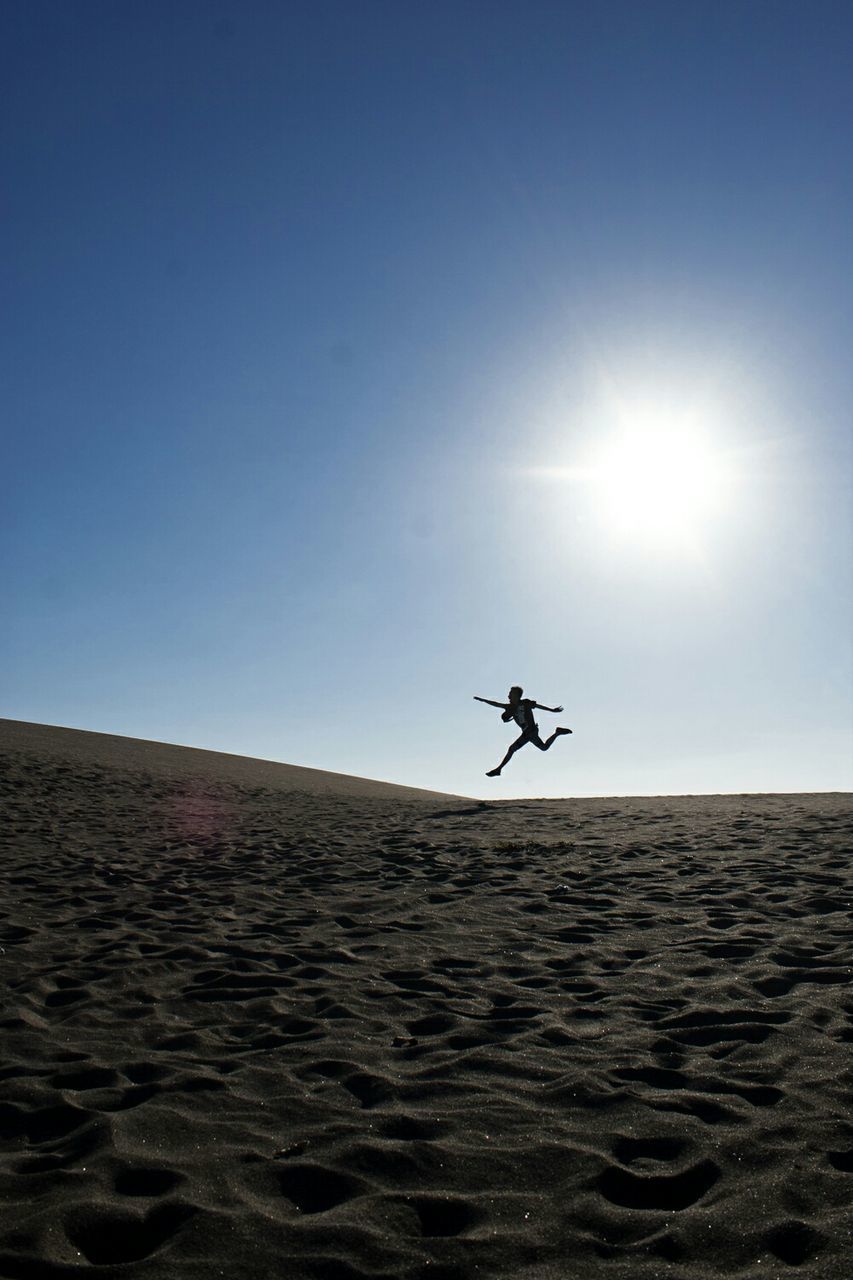 Silhouette of person jumping in desert