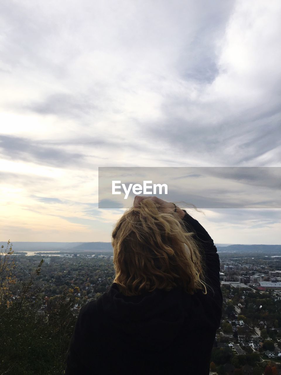 Rear view of woman looking at cityscape against sky