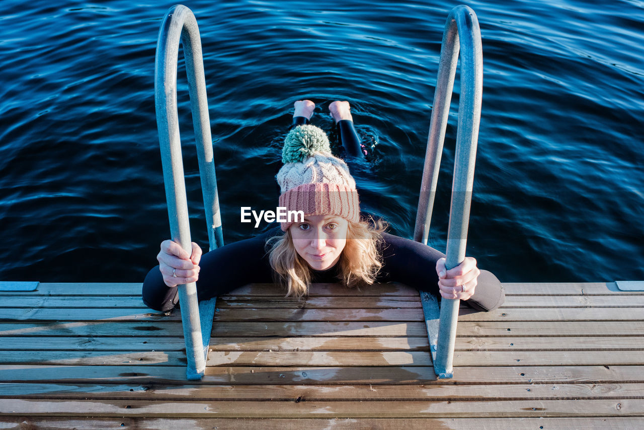 Woman looking up holding onto steps whilst cold water ice swimming