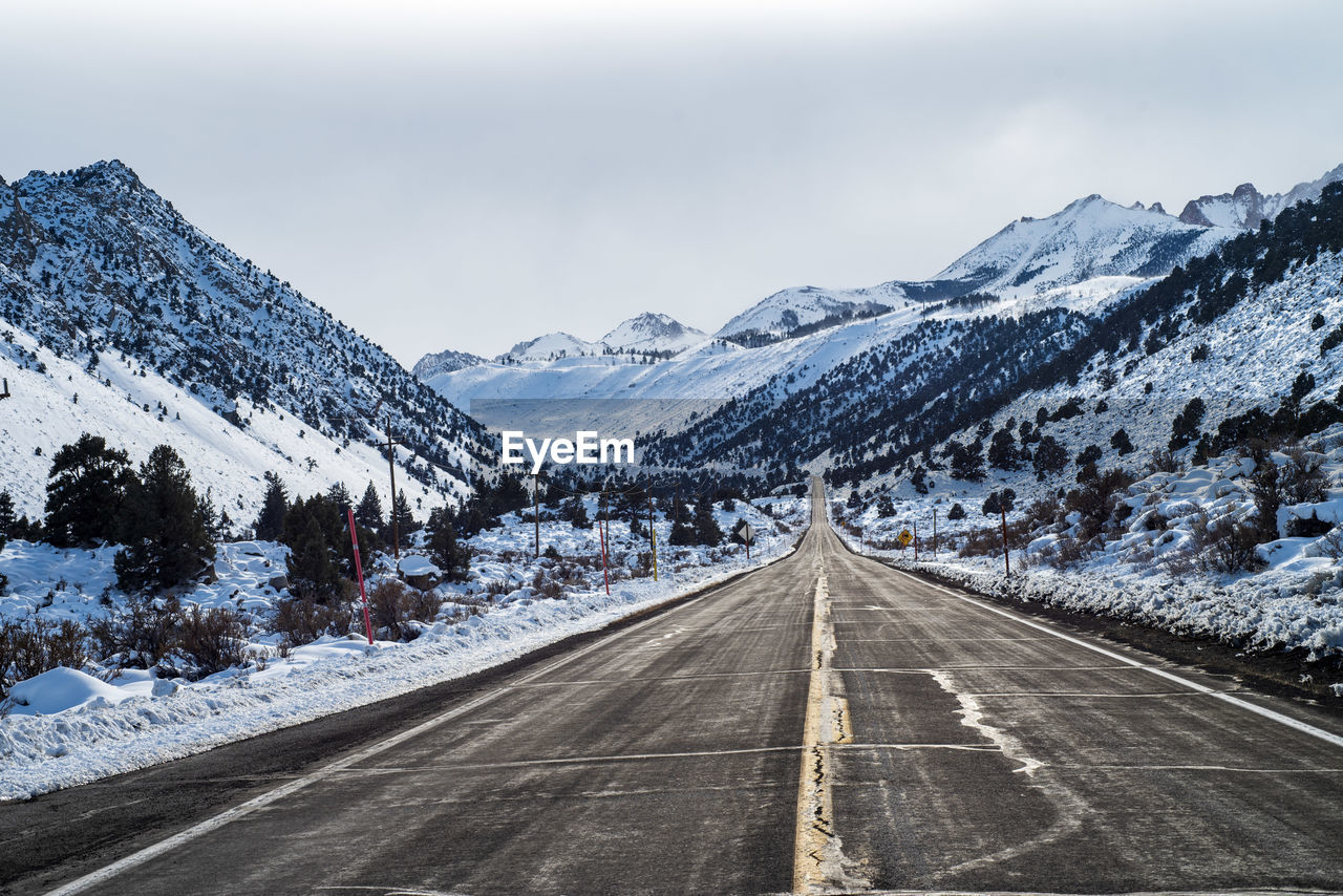 Road leading towards snowcapped mountains against sky