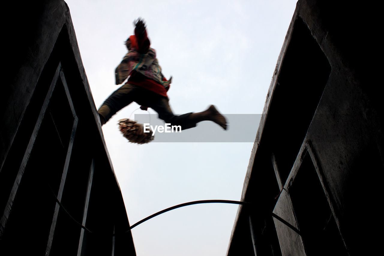 Low angle view of vendor jumping on train against clear sky