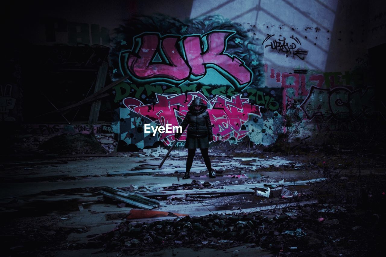 FULL LENGTH OF WOMAN STANDING AT ABANDONED BUILDING