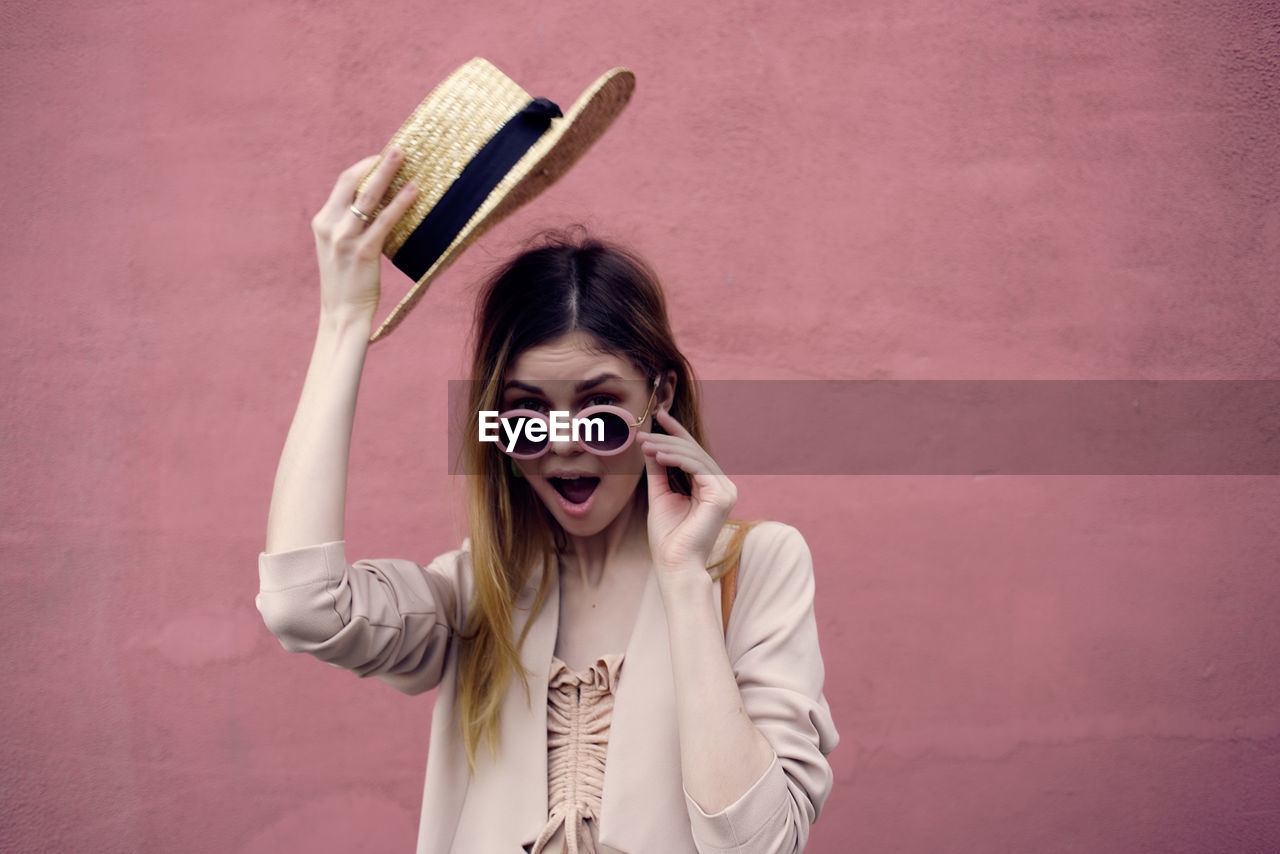 Portrait of woman wearing hat standing against wall