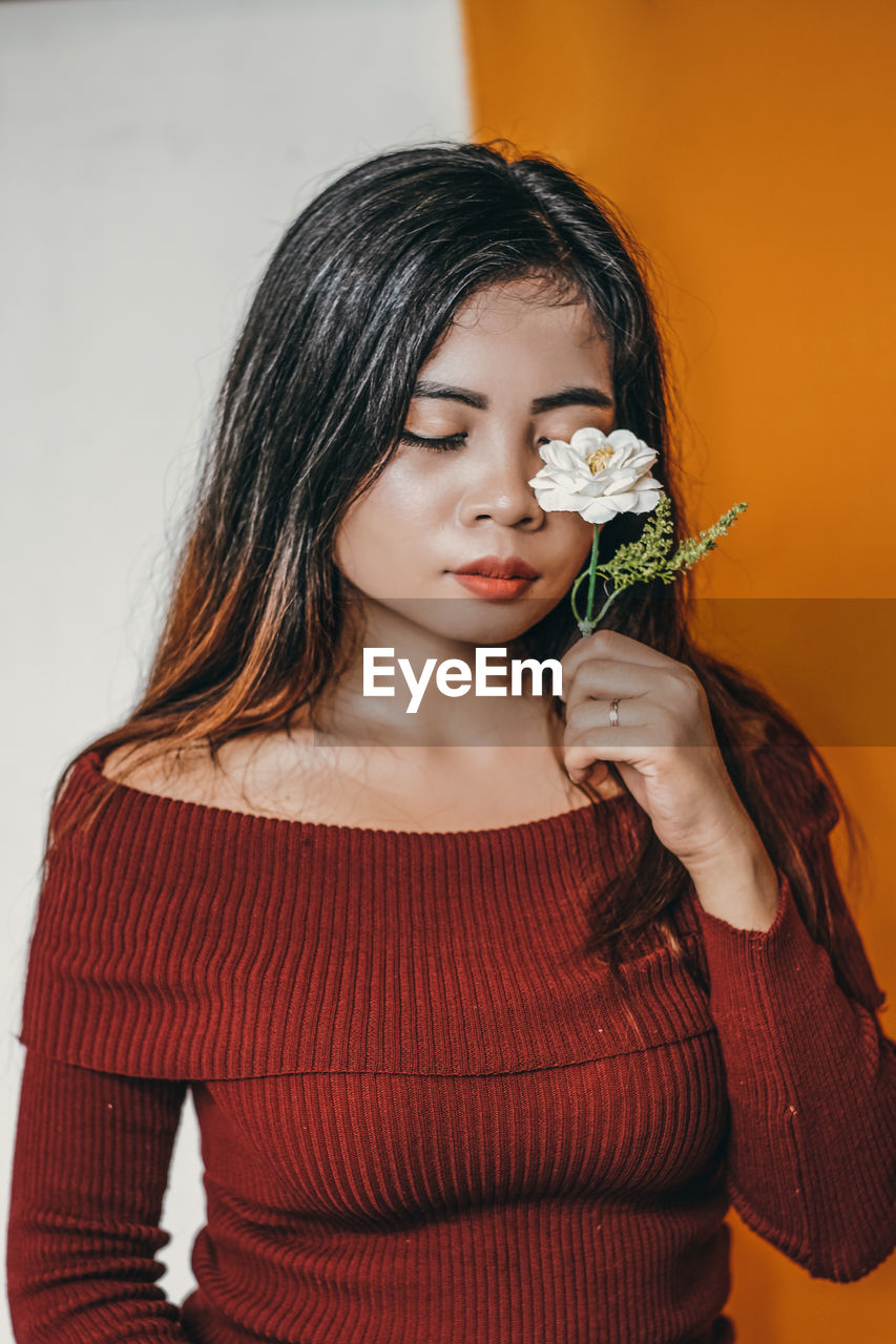 Close-up of a beautiful young woman with white flower