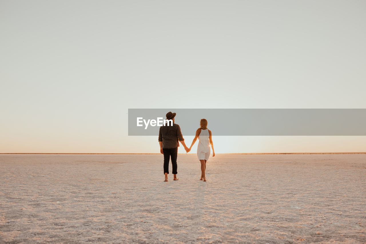 rear view of couple walking at beach