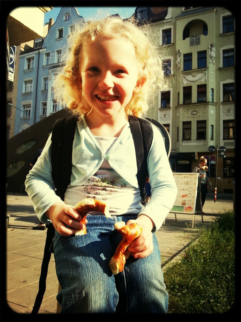 Portrait of happy girl eating bread in city