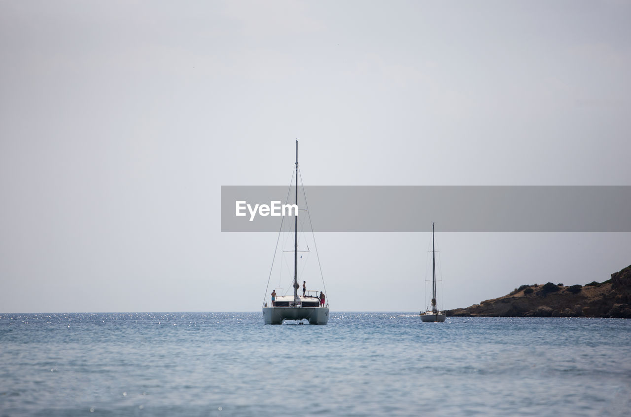 SAILBOAT SAILING IN SEA AGAINST SKY