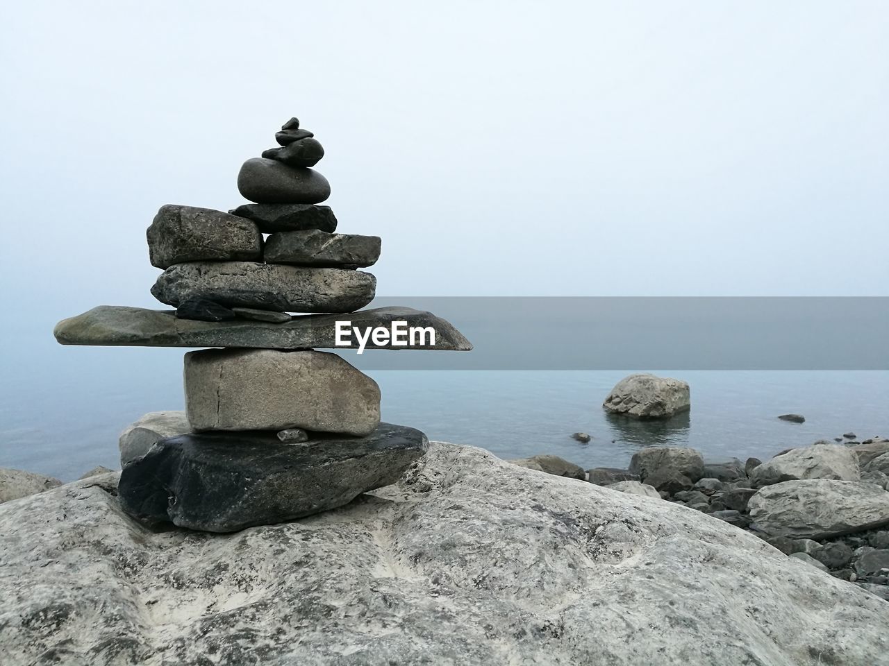 Stack of pebbles by sea against sky